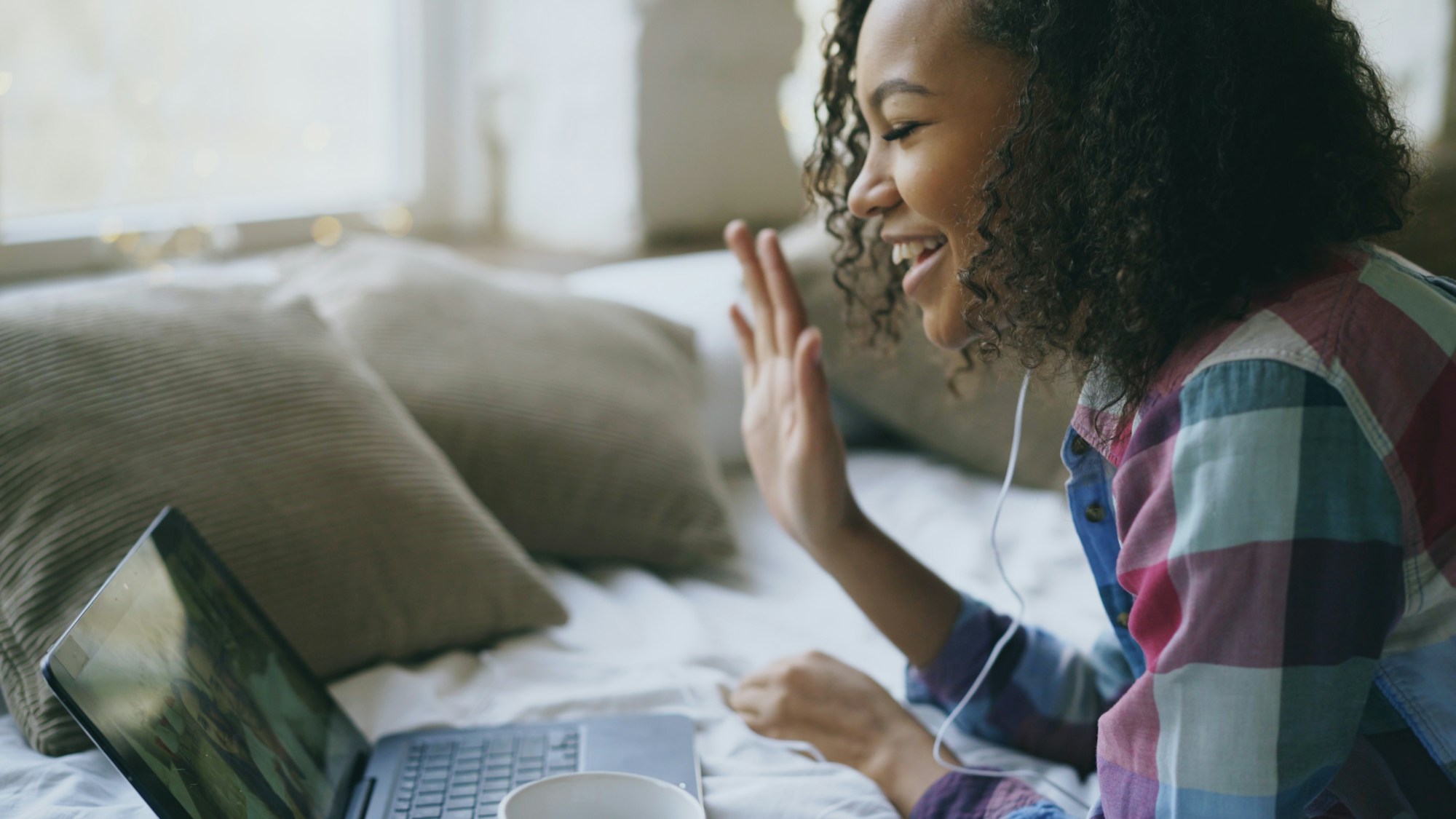 Woman smiling and waving during a video appointment on her laptop at home