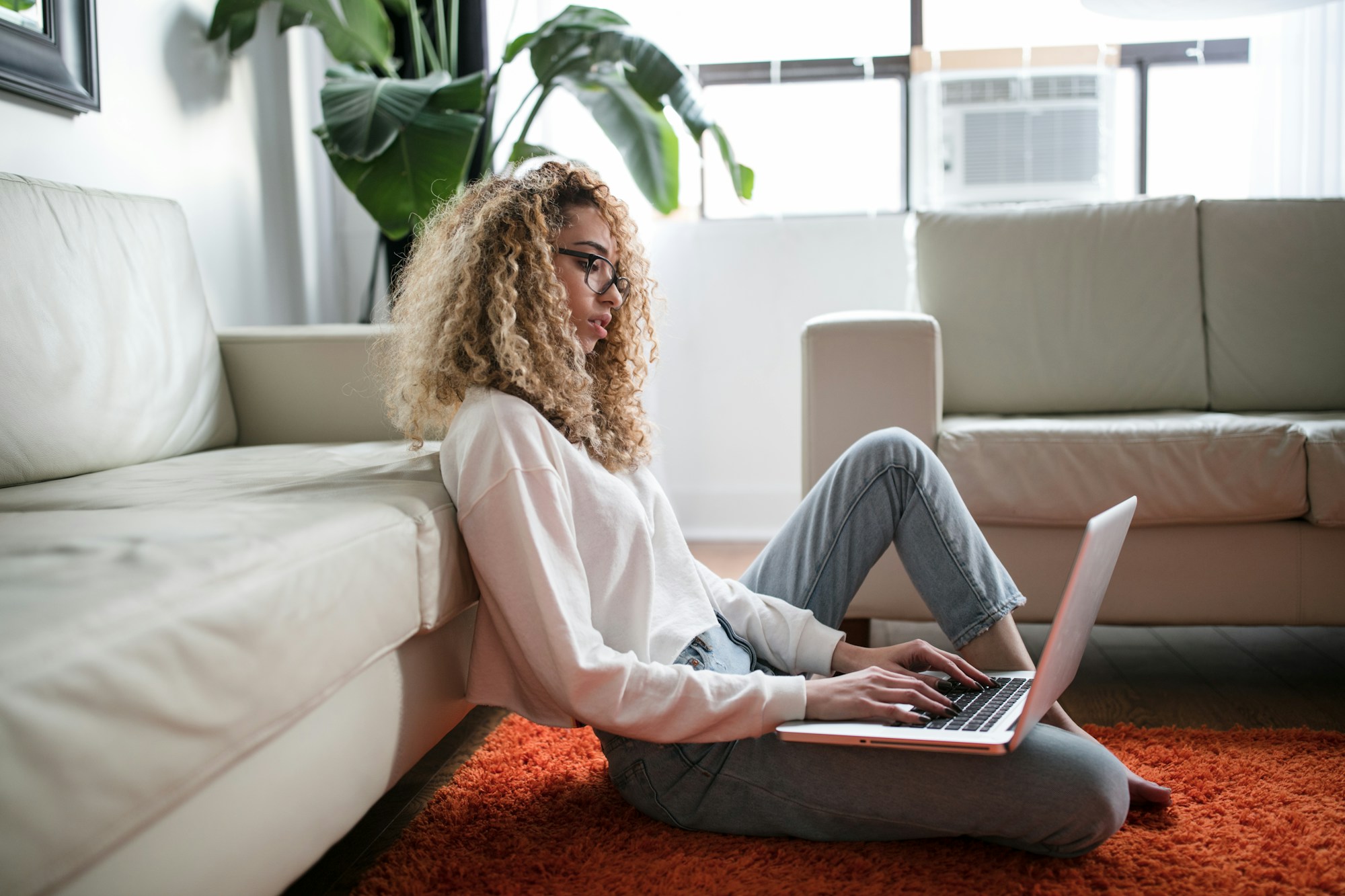 Woman relaxing against her couch while using a laptop